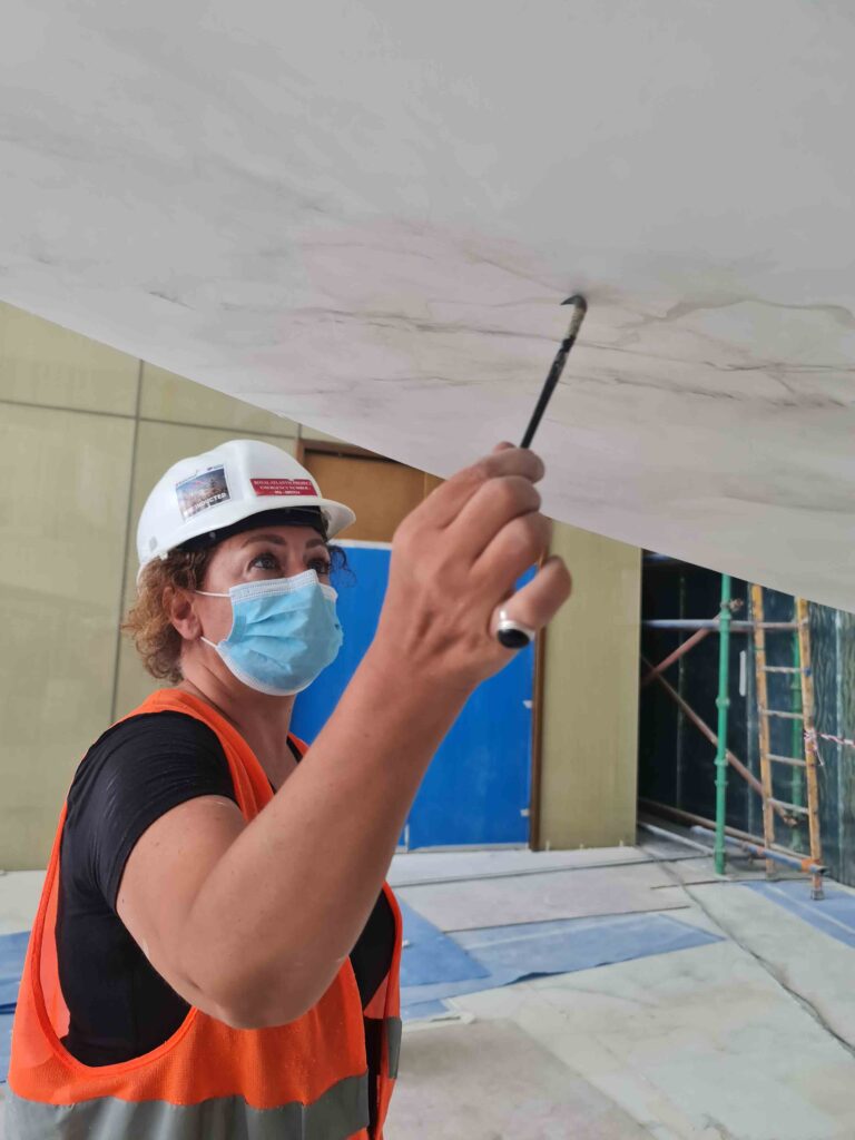 Female artist hand-painting marble effect on interior wall