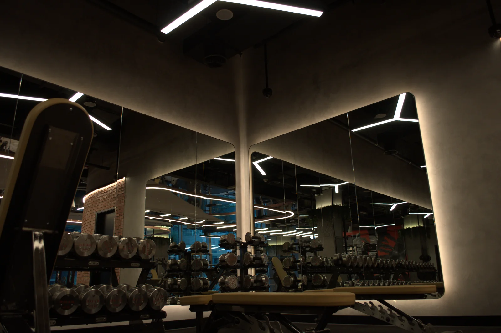 Polished plaster walls around illuminated mirrors in a fitness interior