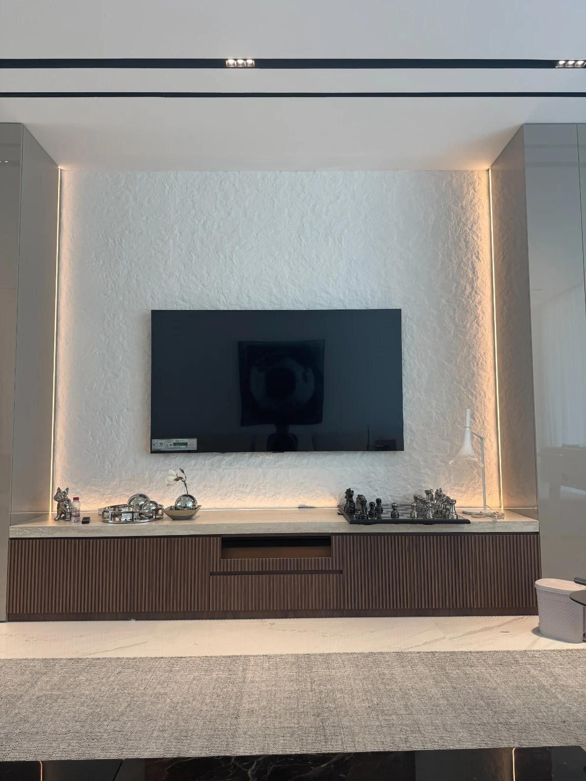 White stone-texture feature wall with warm perimeter lighting